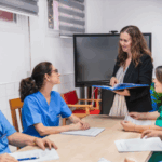 Staff nurses listen attentively as a nurse consultant facilitates a team discussion.