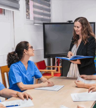 Staff nurses listen attentively as a nurse consultant facilitates a team discussion.