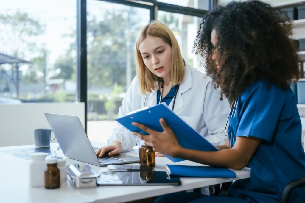 A doctor and a nurse review a medical chart alongside clinical research to support evidence-based care decisions.