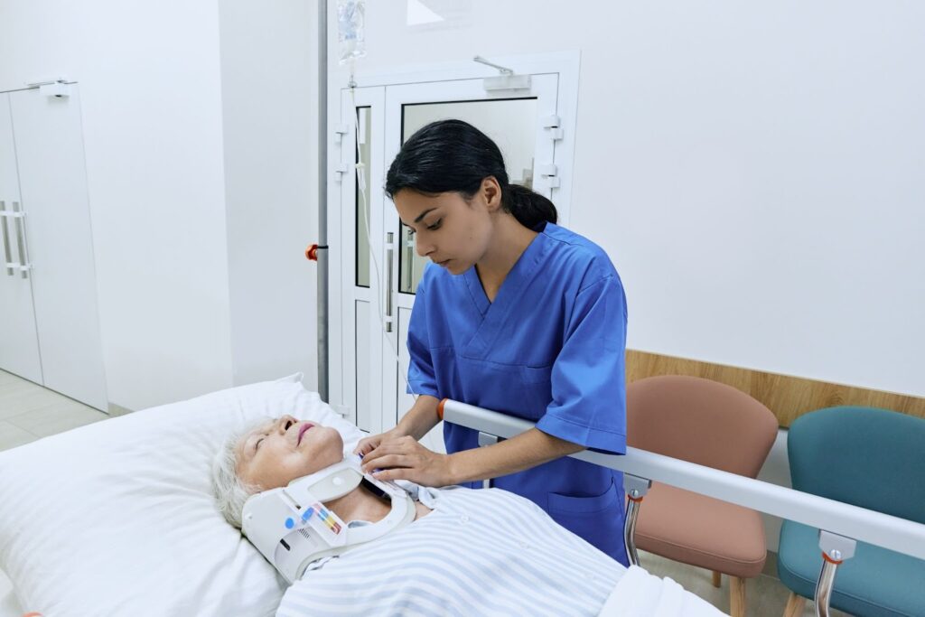 A nurse puts a cervical collar on an injured woman lying on a hospital gurney.