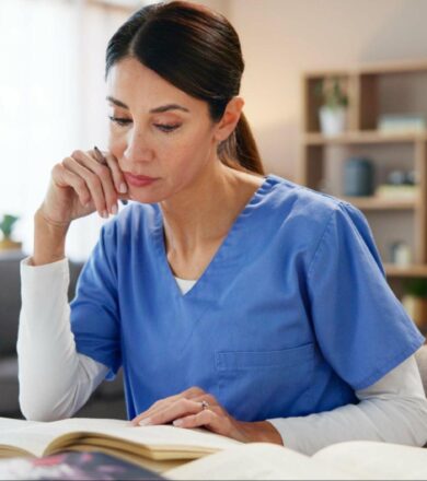 Nurse using textbook and laptop to plan care based on medical research and evidence.
