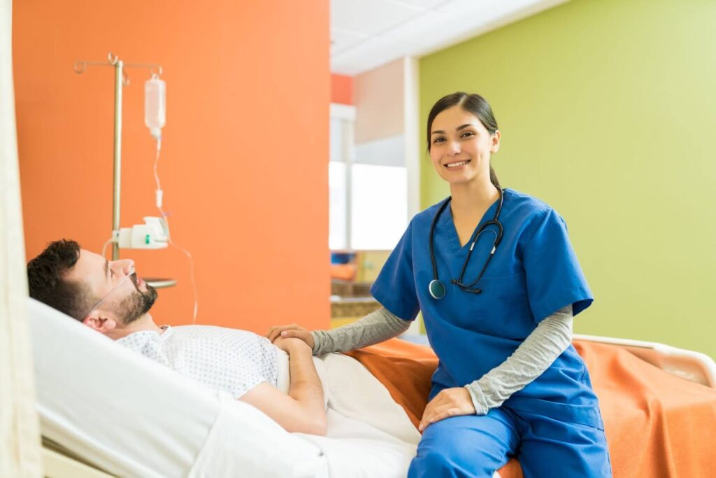 A nurse smiles while examining a patient on a hospital bed.
