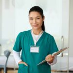 A nurse smiles while carrying a clipboard and making her rounds.