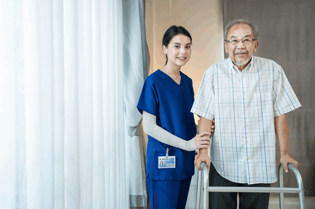 A nurse helps an elderly man stand with his walker.